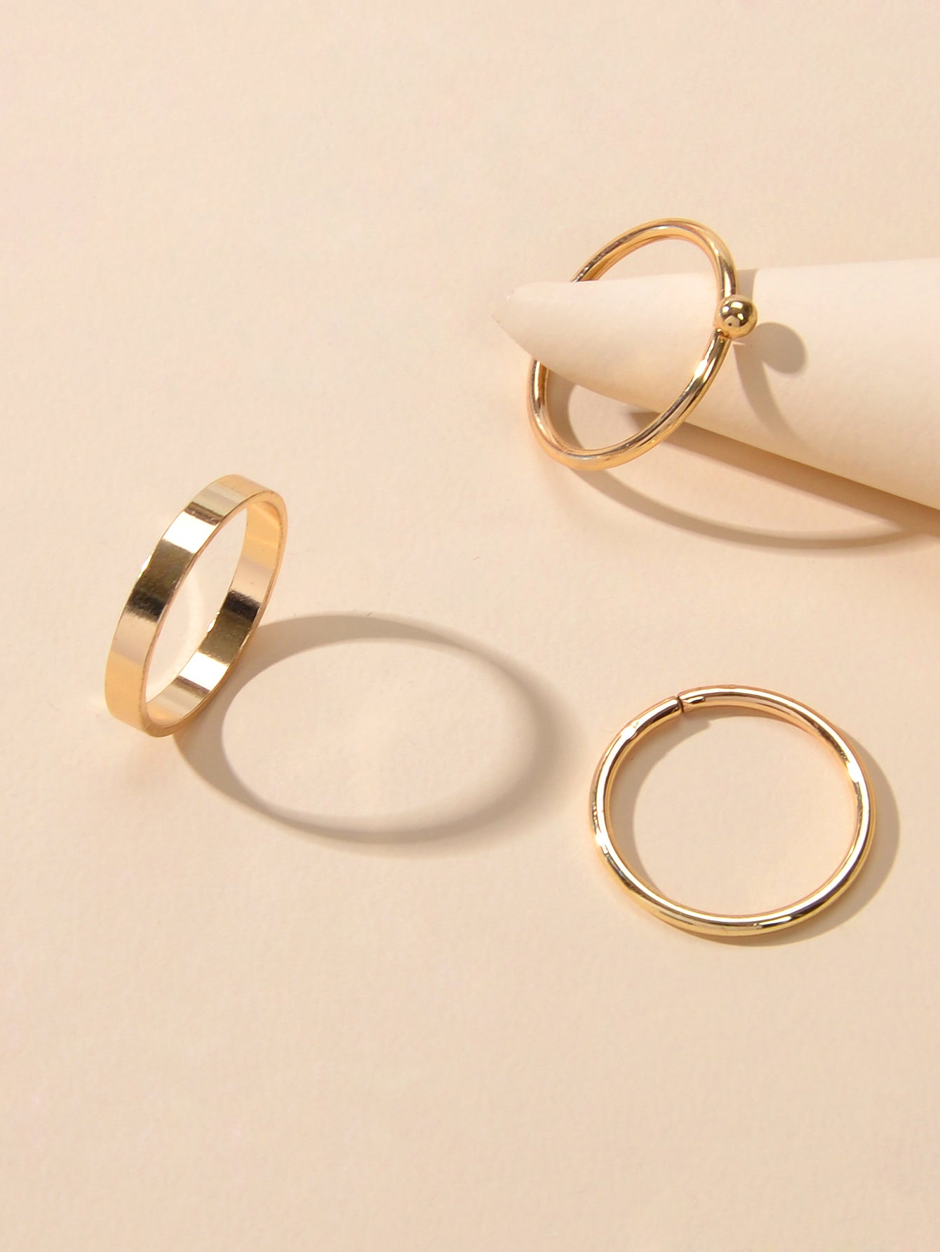 Minimalist gold stackable ring set featuring three polished metal bands arranged gracefully together — view 3