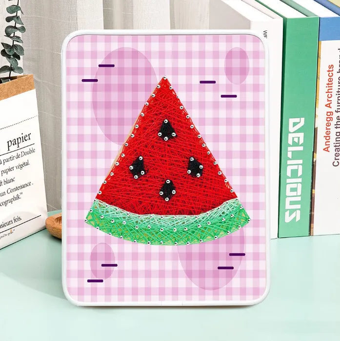 Watermelon string art craft kit with pins, colorful thread, wooden board, and display stand.