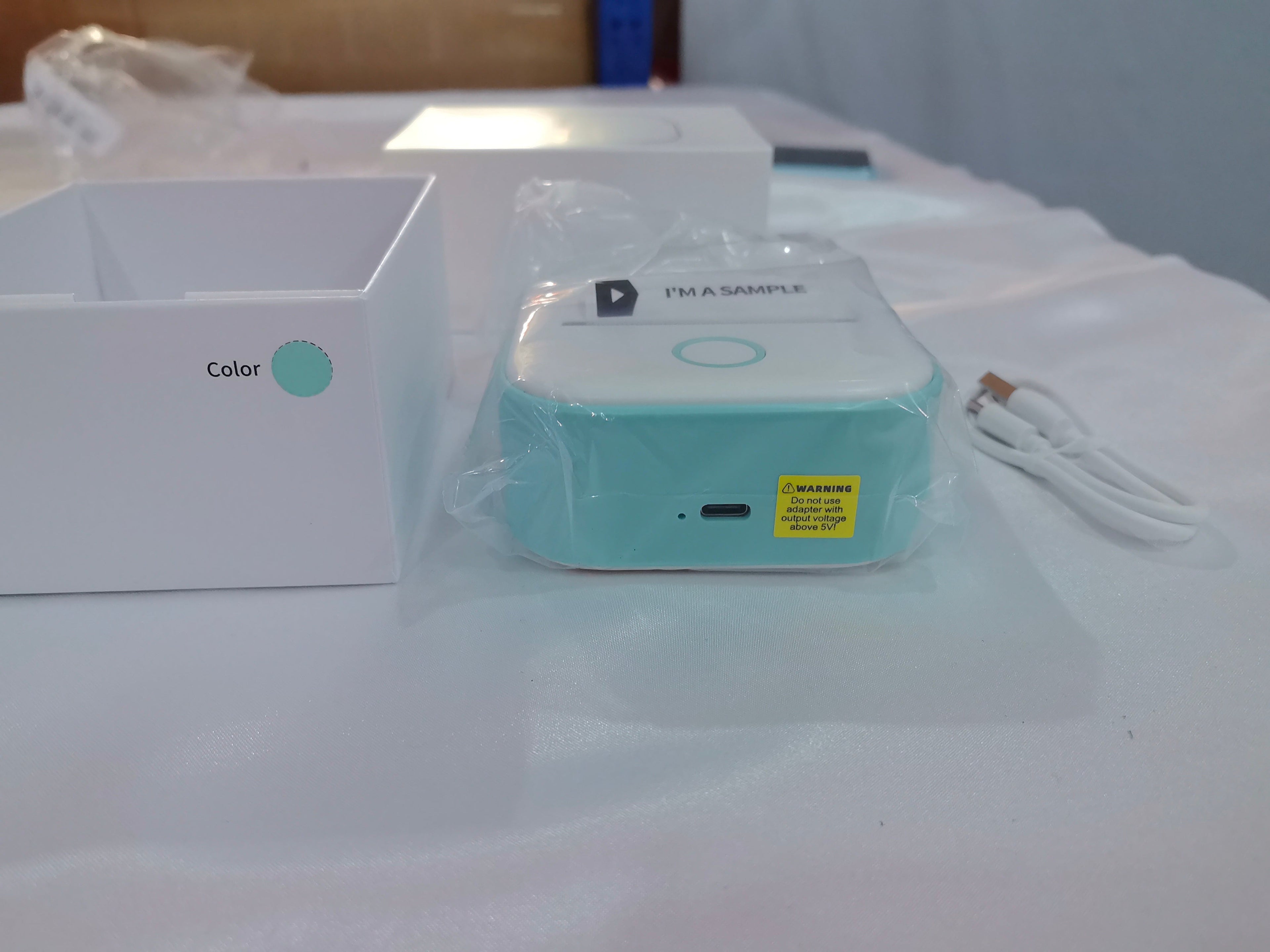White portable mini thermal pocket printer dispensing a sticky label for home office organization — view 4