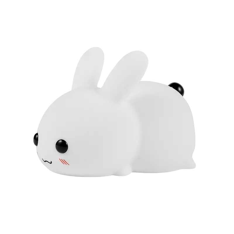 White squishy silicone bunny night light glowing with soft colors beside a remote control
