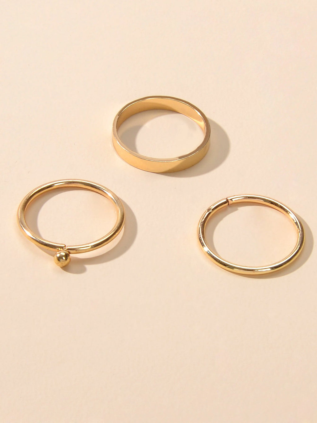 Minimalist gold stackable ring set featuring three polished metal bands arranged gracefully together — view 4
