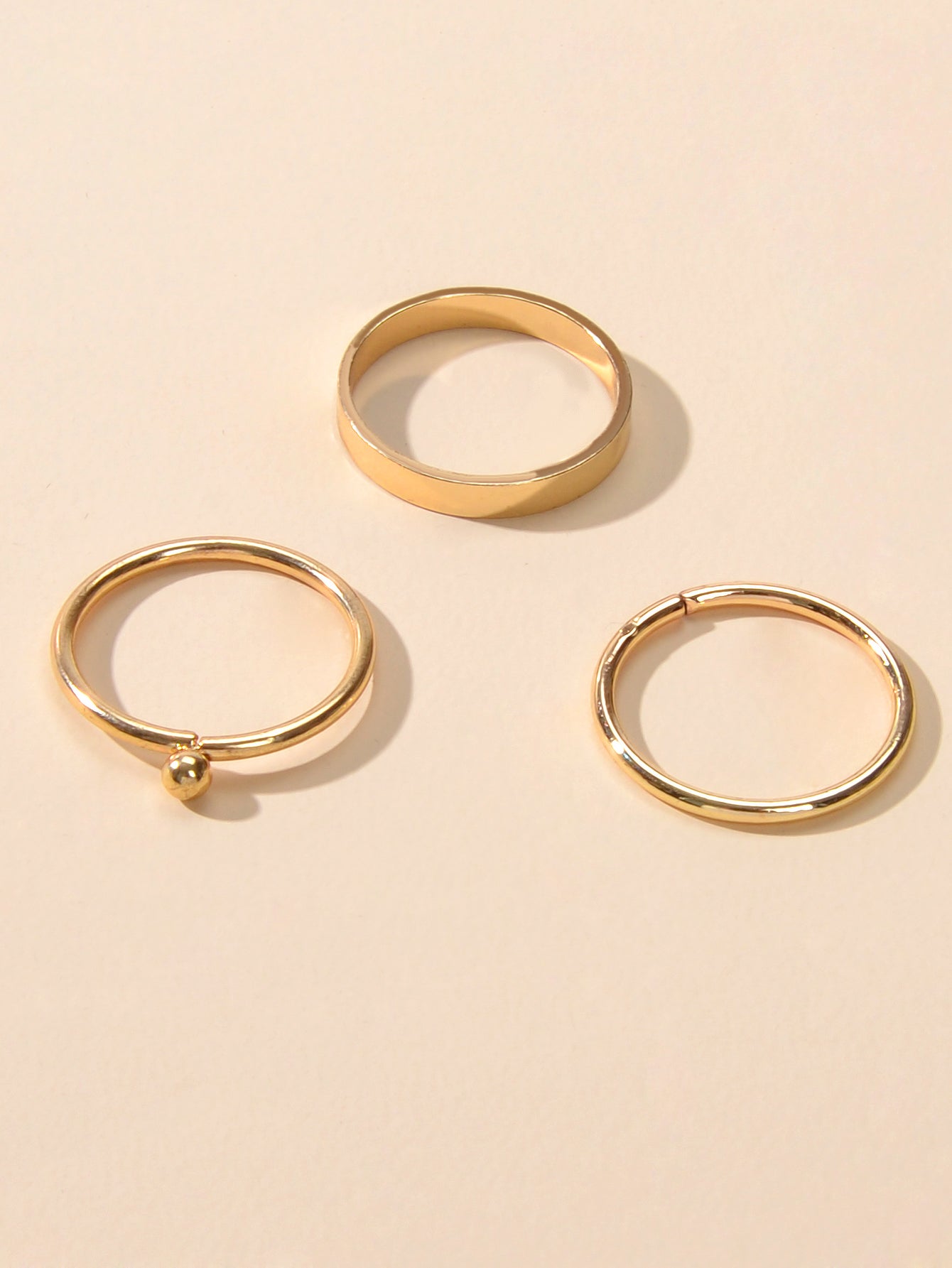 Minimalist gold stackable ring set featuring three polished metal bands arranged gracefully together — view 4