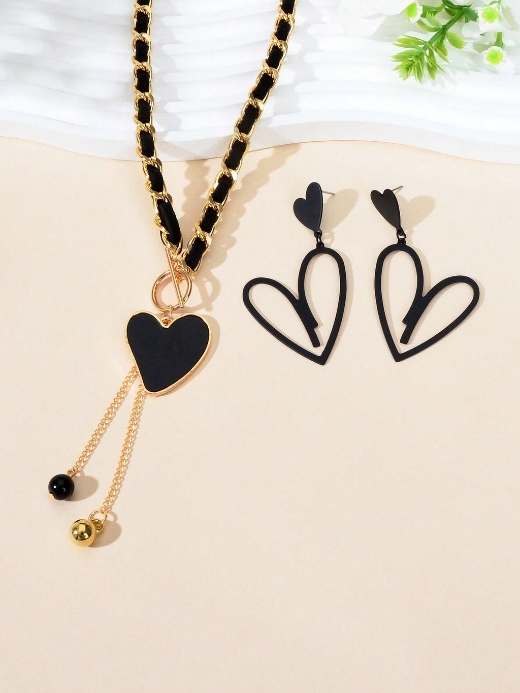 Black heart pendant necklace and matching earrings set crafted from polished metal with dark centerpieces. — view 5