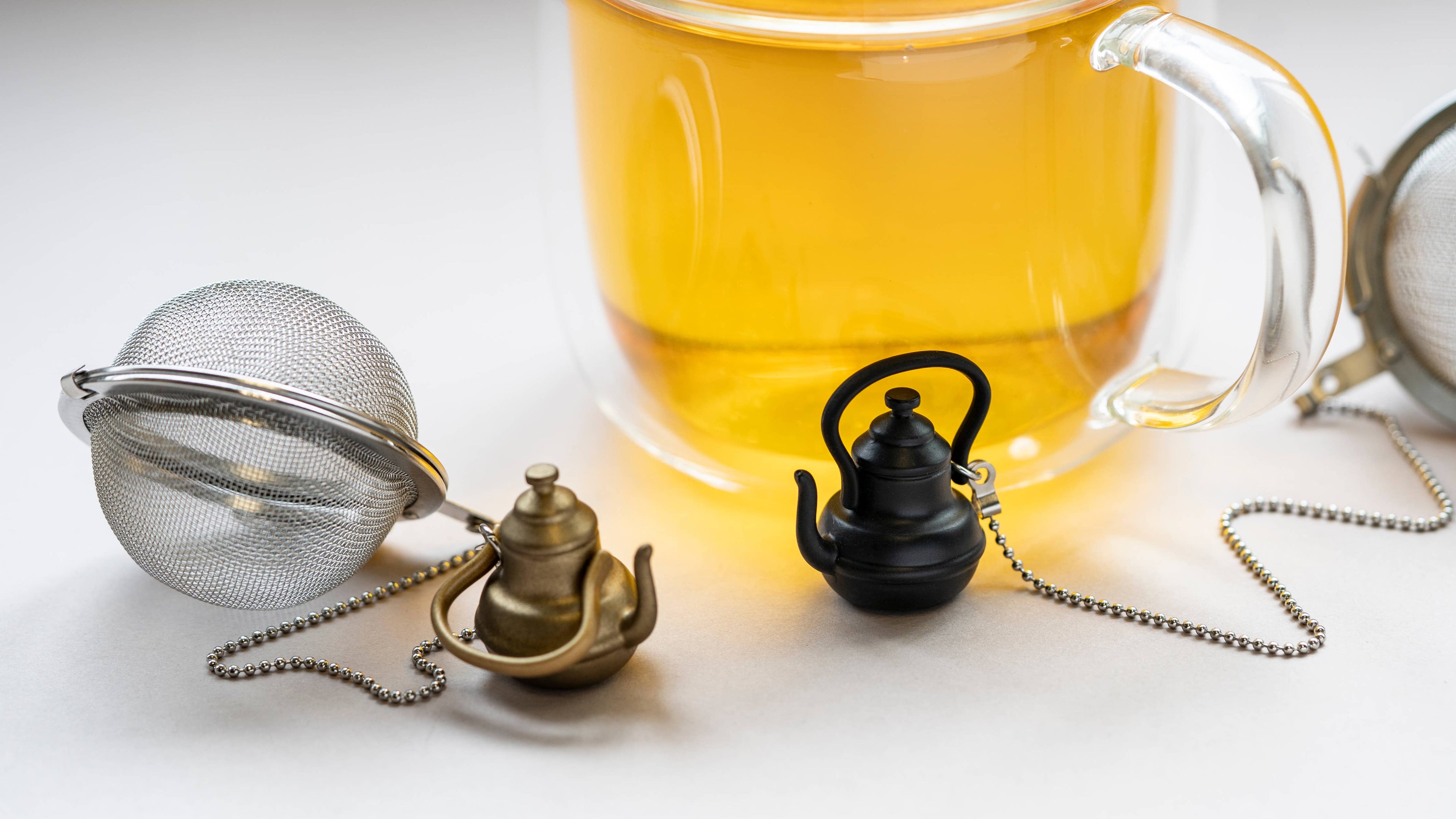Stainless steel mesh tea infuser ball with a decorative gold teapot charm and metal chain — view 2