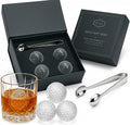 Four glass golf ball whiskey chillers with stainless steel tongs inside a premium cotton lined box