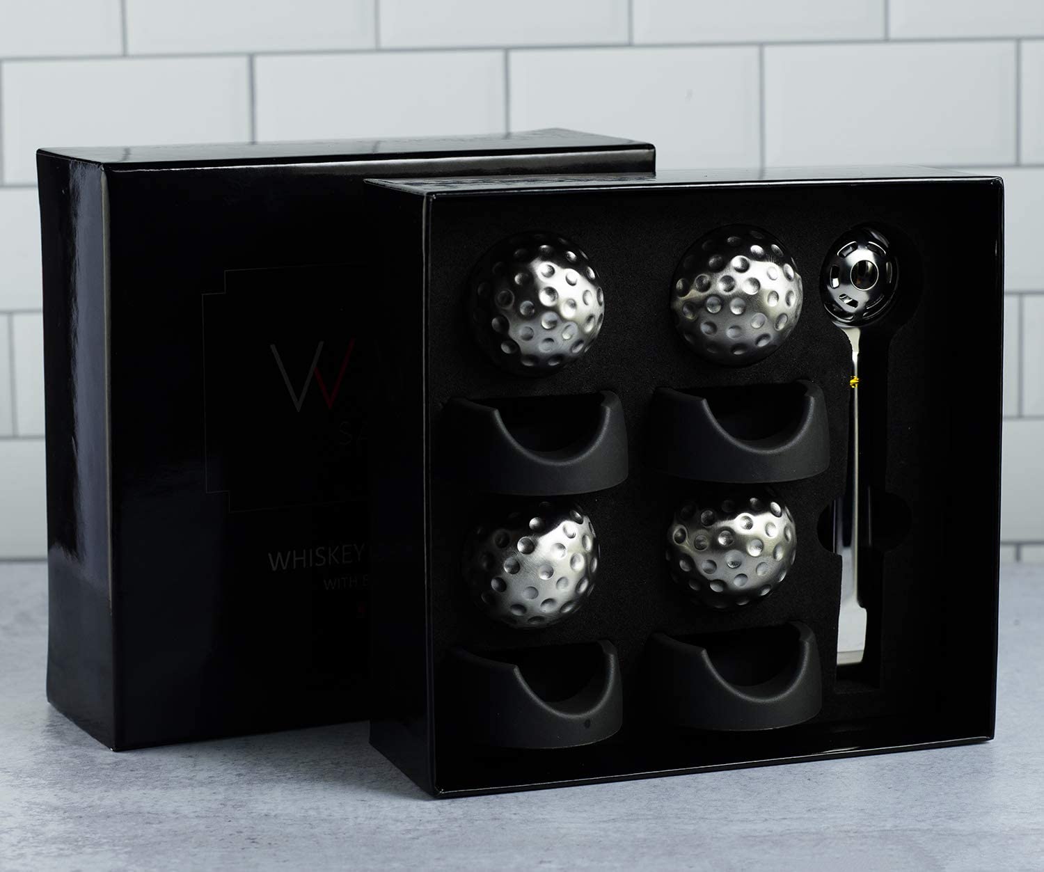 Stainless steel golf ball shaped whiskey stones chilling in a crystal glass of bourbon — view 3