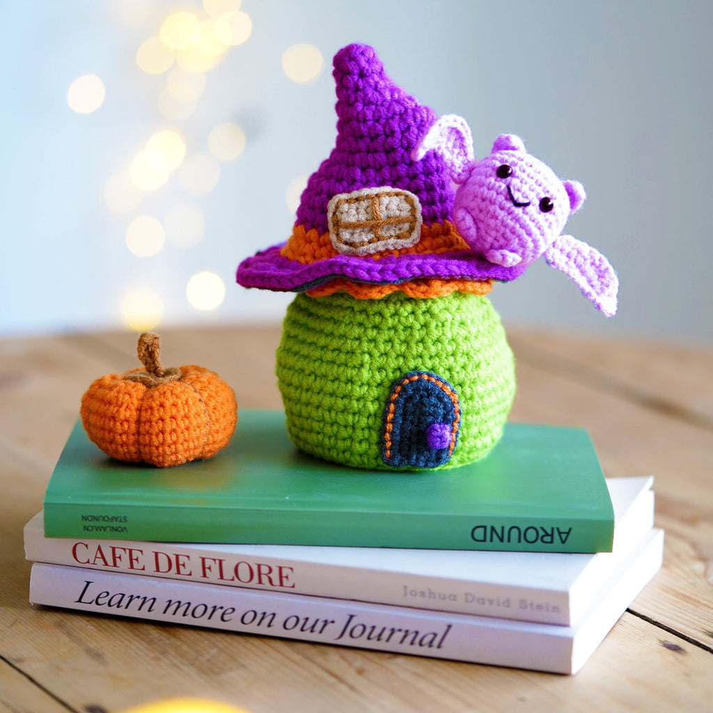Halloween amigurumi DIY crochet kit featuring a completed miniature witch house, flying bat, and pumpkin