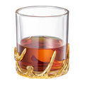 Clear double old fashioned whiskey glass resting on an intricate gold antler style base