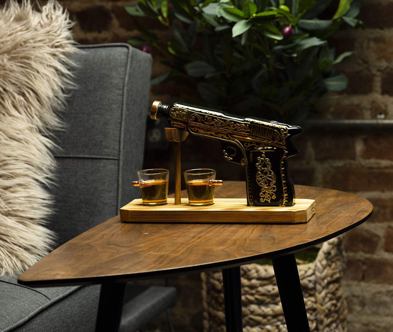 Black and gold hand-painted pistol whiskey decanter with two shot glasses on wooden display stand — view 2