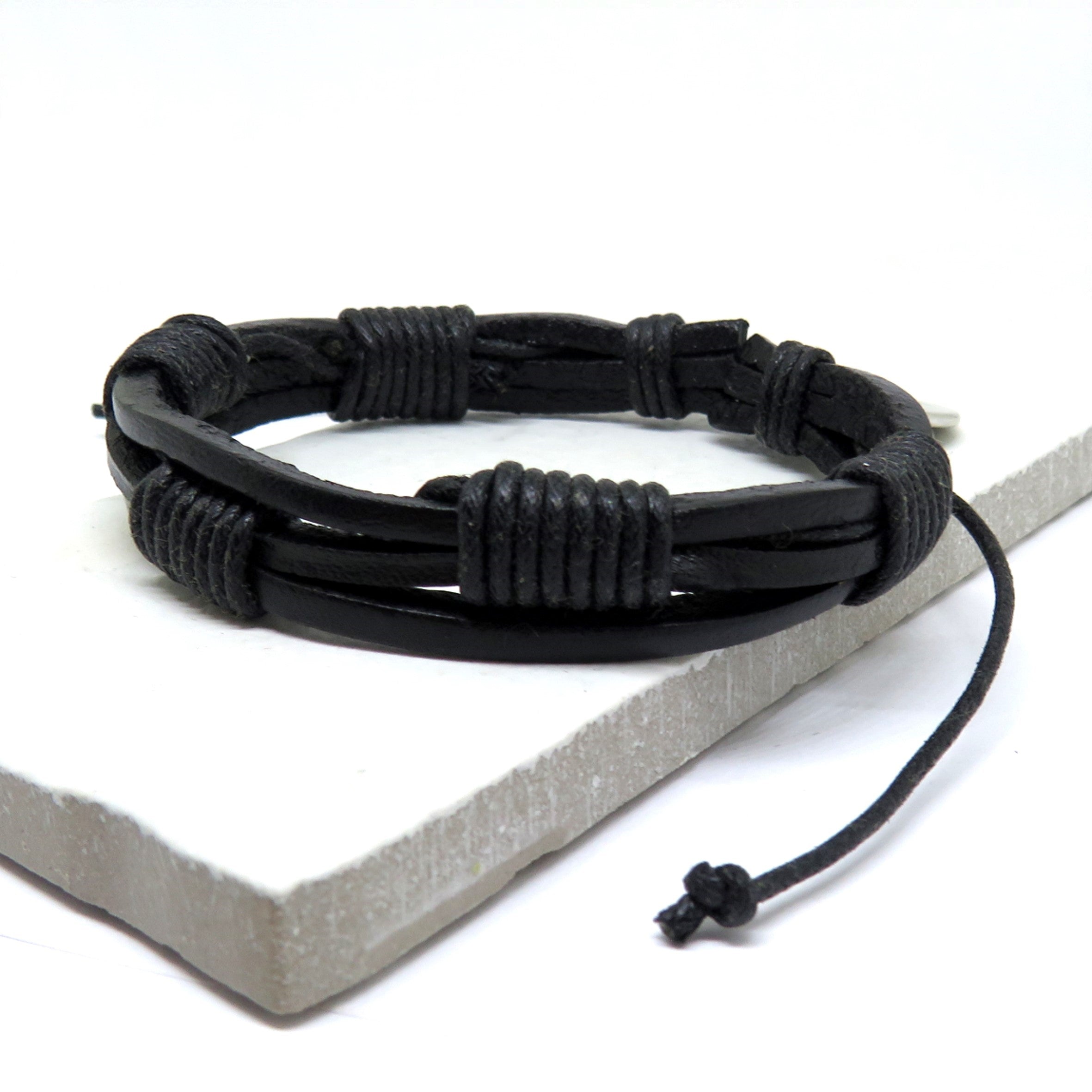 Men's black multi-strand leather and woven cord bracelet displayed in a sophisticated dark gift box