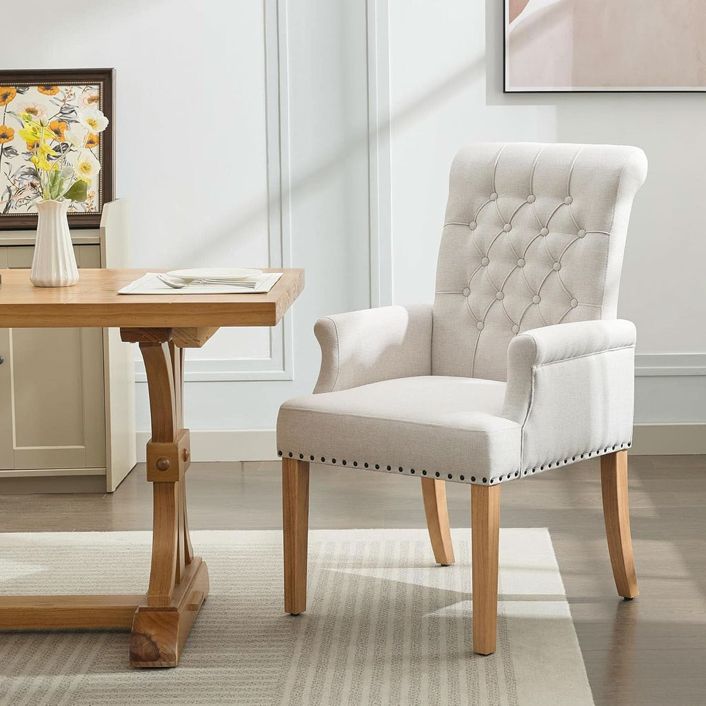 Beige upholstered dining chair with armrests, tufted backrest, and solid wood legs on a neutral background