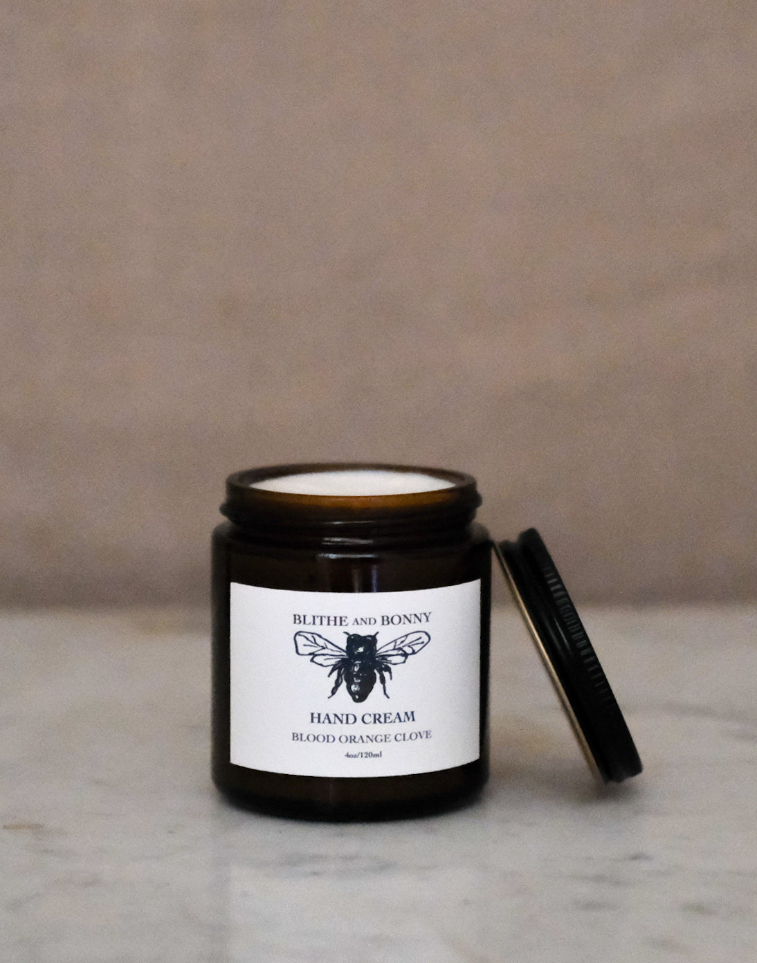 Luxurious vegan hand cream in a four ounce amber glass jar with a metal lid
