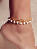 Multi-layer gold and silver tone chain anklet with white beads and leaf pendant on foot