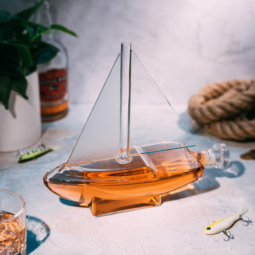 Glass sailboat whiskey decanter with built-in spigot resting on a sturdy wooden display base — view 2
