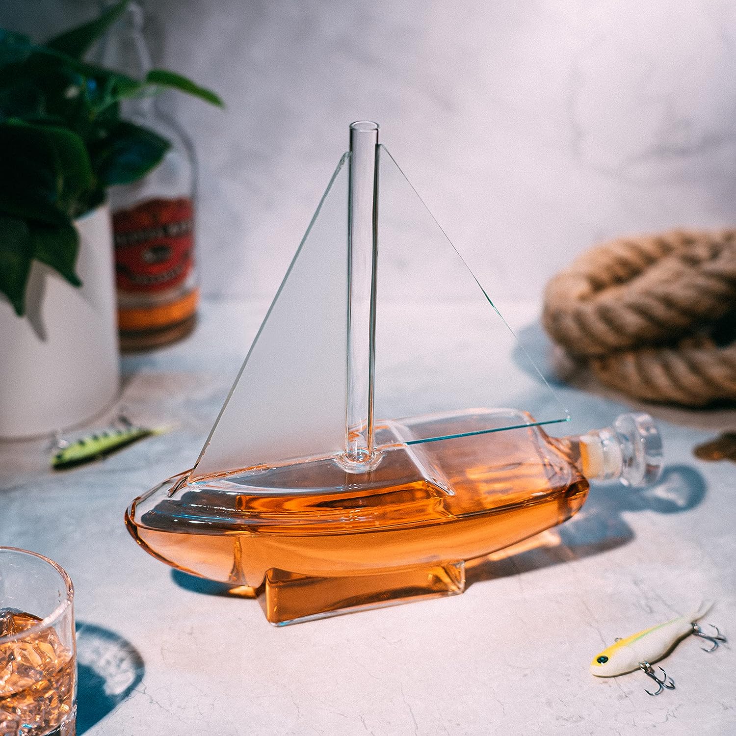 Glass sailboat whiskey decanter with built-in spigot resting on a sturdy wooden display base — view 2