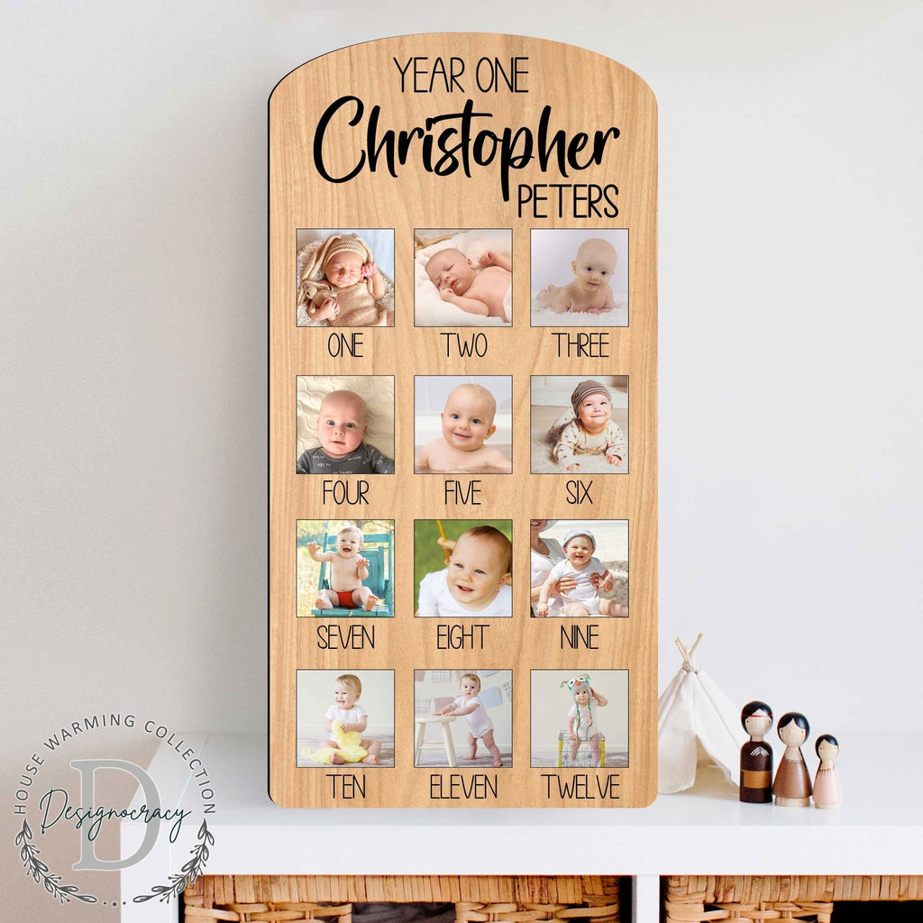 Custom wooden baby milestone photo board displaying twelve months of pictures with personalized cut out name