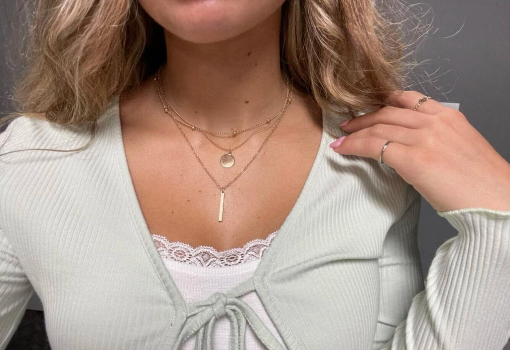 Boho multi-layer charm necklace with bar, disc, and round bead pendants on adjustable metallic chain. — view 4