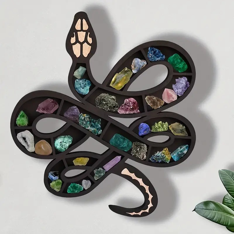 Black wooden snake shaped wall shelf displaying crystals and small plants on a wall — view 2