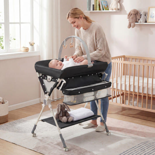 Black foldable baby changing table station with storage bag, bottom shelf, and wheels.