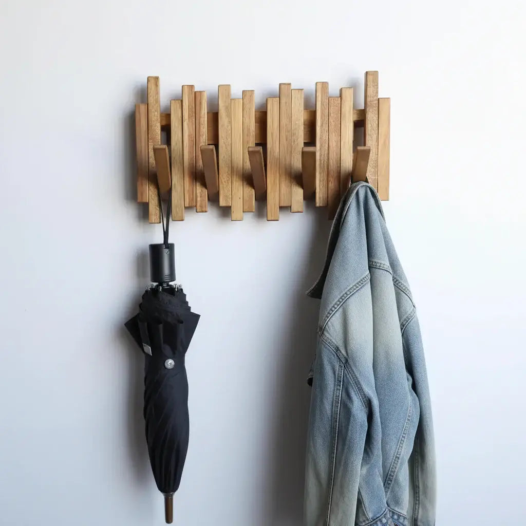 Acacia wood wall mounted coat rack with flip down hooks hanging in a modern entryway — view 3