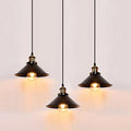 Three black industrial metal pendant lights hanging over a dining table with vintage Edison bulbs.