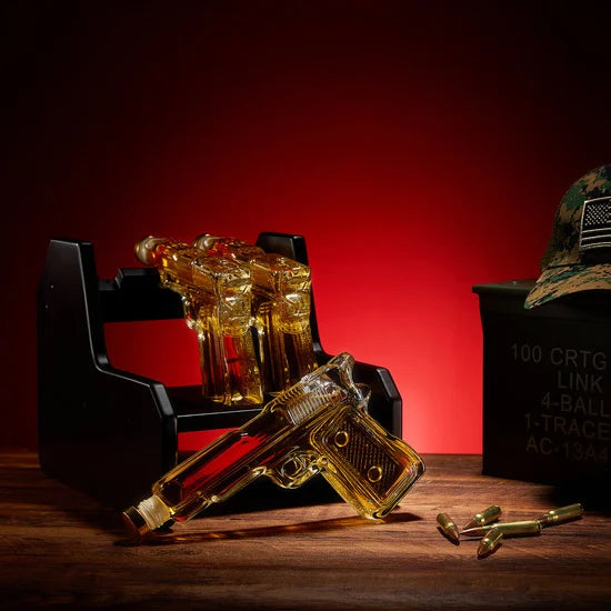 3-pistol whiskey decanter set made of glass resting on a rich mahogany wood display base — view 2