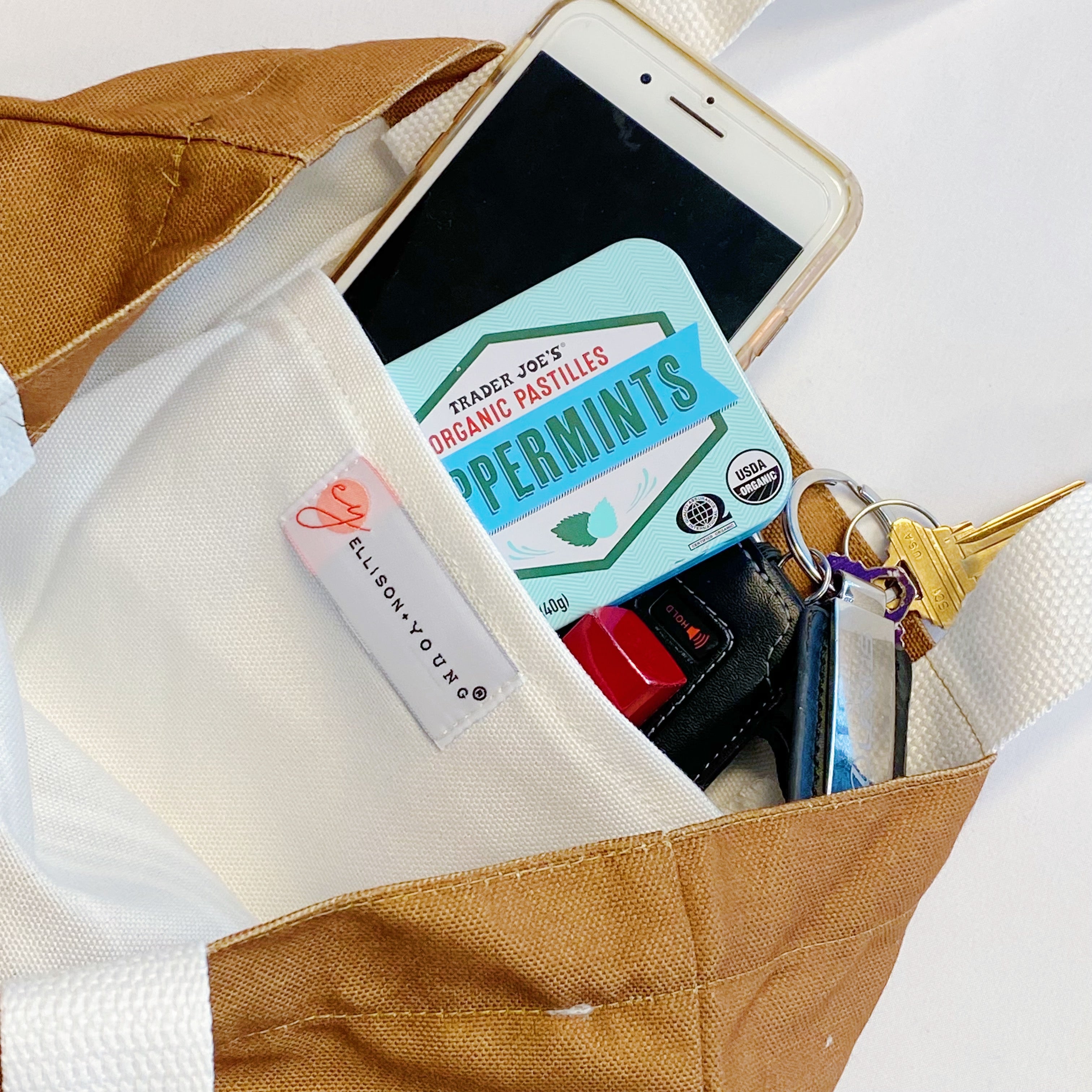 White canvas tote bag with graphic print and shoulder strap carrying books and a laptop — view 4