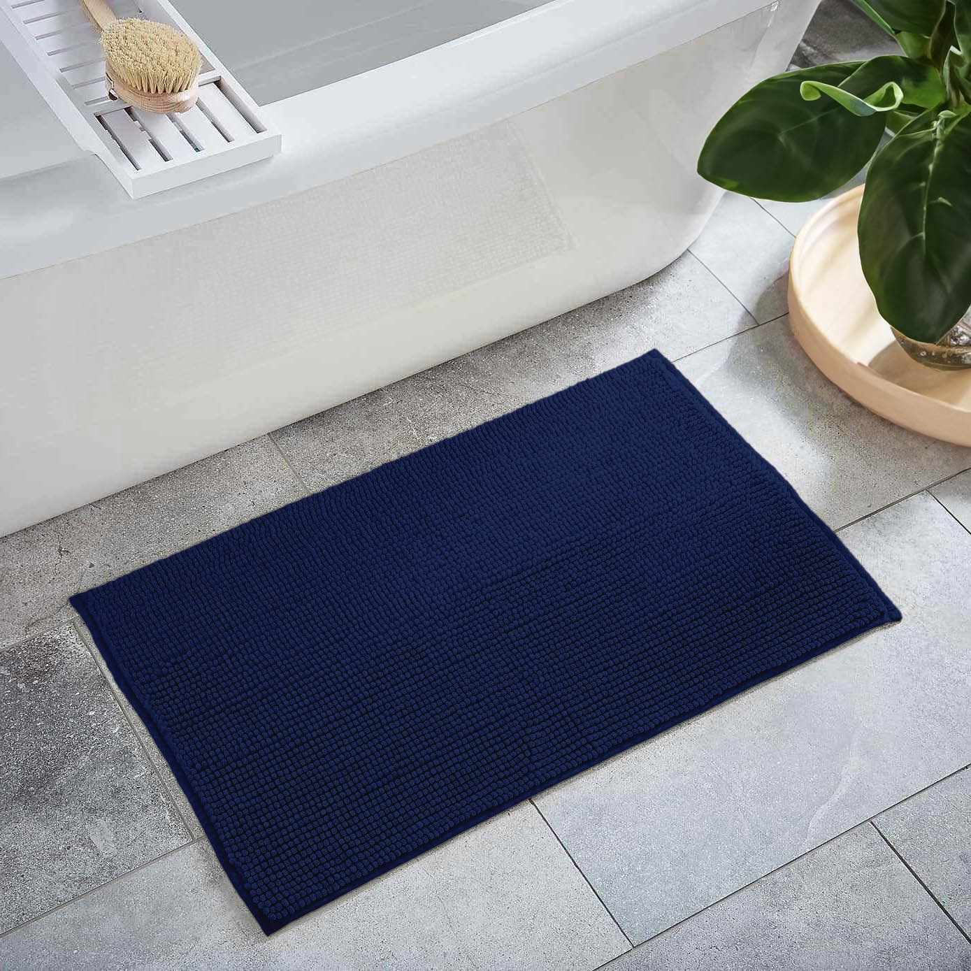 Plush navy blue washable bath mat with thick polyester shag texture on a bathroom floor