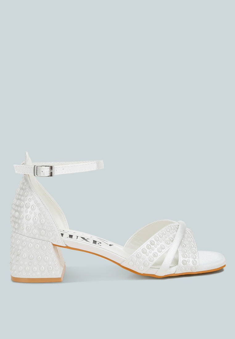 White satin low block heel sandals featuring elegant pearl embellished midfoot straps and adjustable buckles