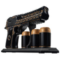 Black hand painted pistol whiskey decanter with three shot glasses on wooden display stand