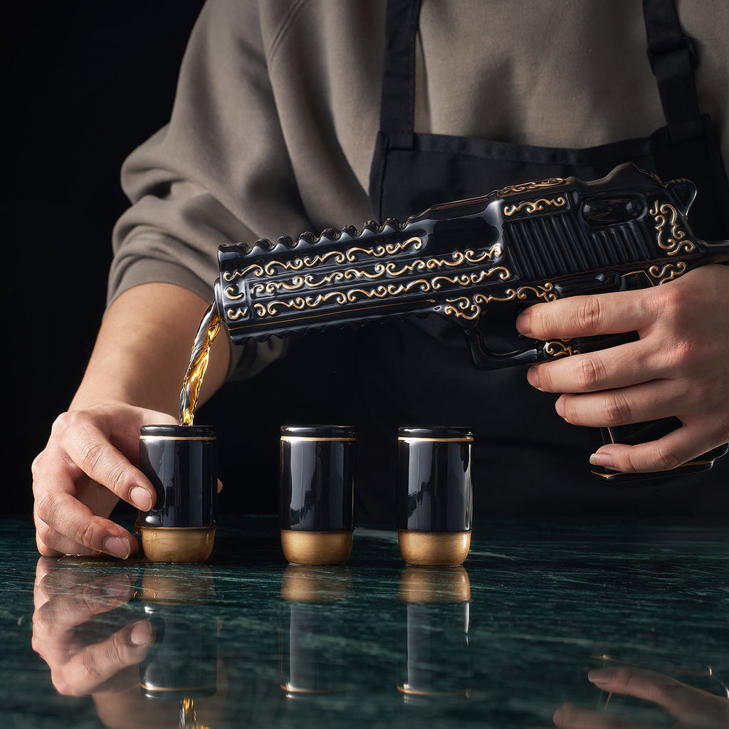 Black hand painted pistol whiskey decanter with three shot glasses on wooden display stand — view 2