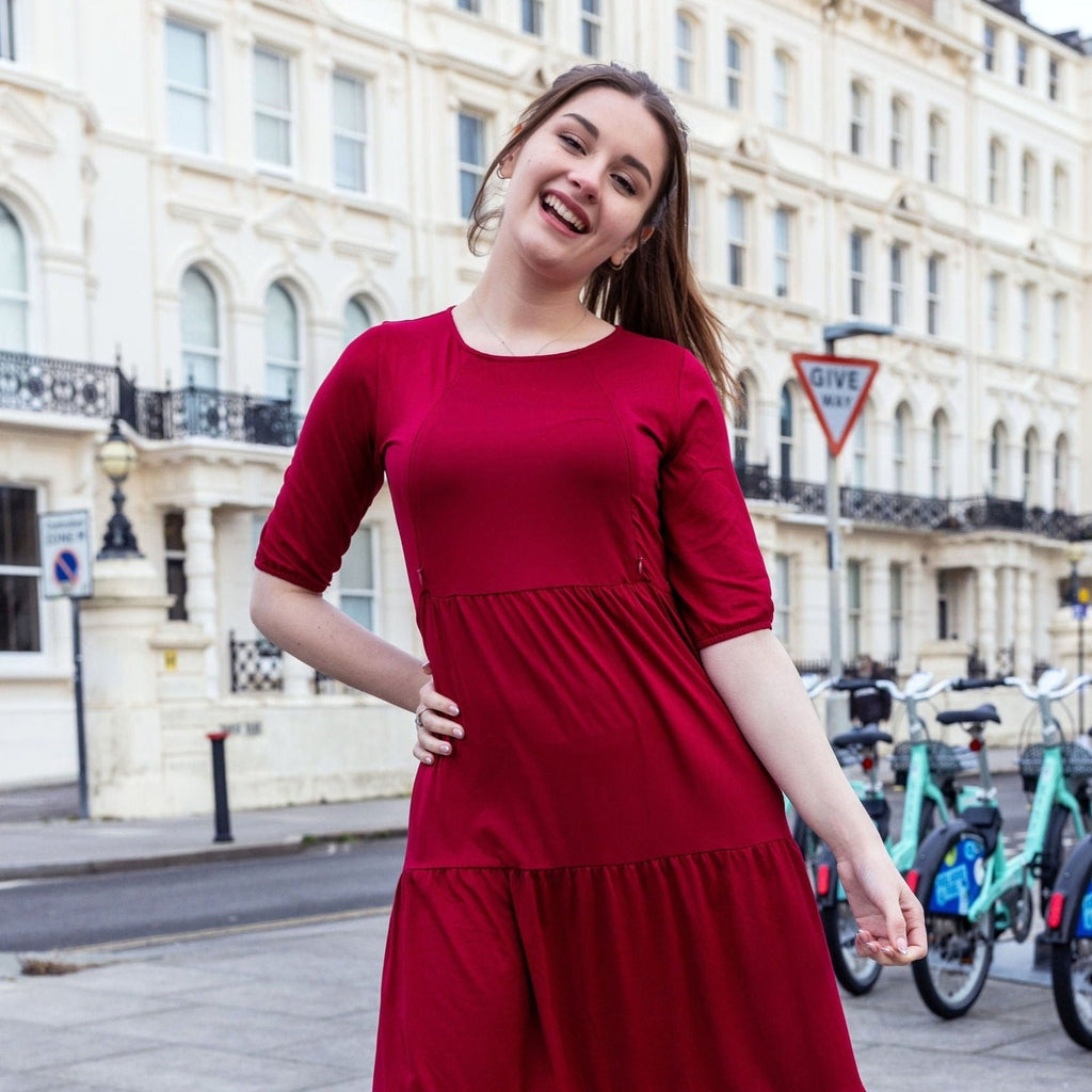 Burgundy cotton nursing midi dress featuring discreet zips, smock fit, and large pockets worn by model — view 3