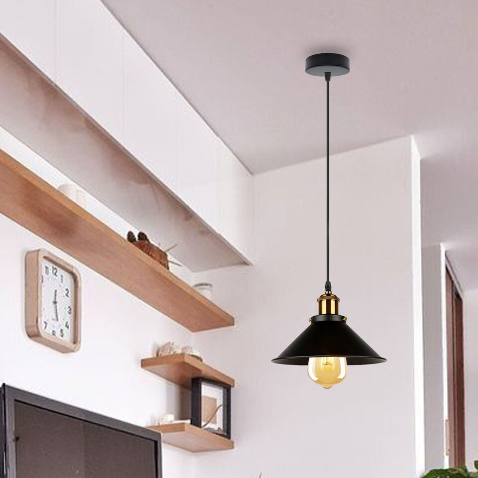 Three black industrial metal pendant lights hanging over a dining table with vintage Edison bulbs. — view 2
