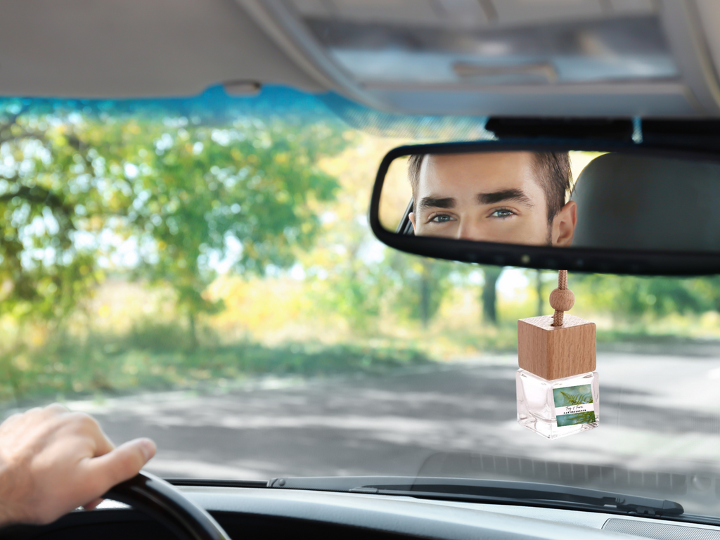 Glass hanging car freshener bottle with wooden cap and hanging rope, showcasing amber liquid inside.