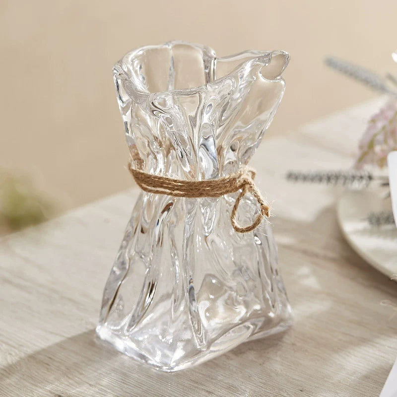 Wrinkled glass vase with natural twine accent and folded paper texture on a modern table — view 4
