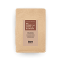 Freshly roasted Colombia Tolima whole coffee beans displayed in an eco-friendly kraft paper bag.