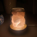 AURORA natural quartz crystal essential oil diffuser with wooden base and glass reservoir illuminated.