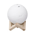 White LED moon lamp aroma diffuser resting on a wooden base with mist emitting from top
