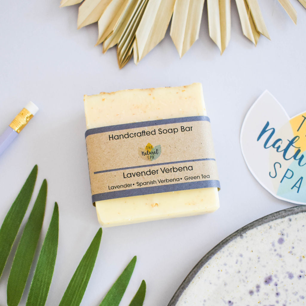 Handmade natural lavender verbena soap bar displayed with botanical ingredients and a rich creamy lather