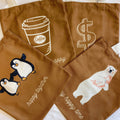 White canvas tote bag with graphic print and shoulder strap carrying books and a laptop