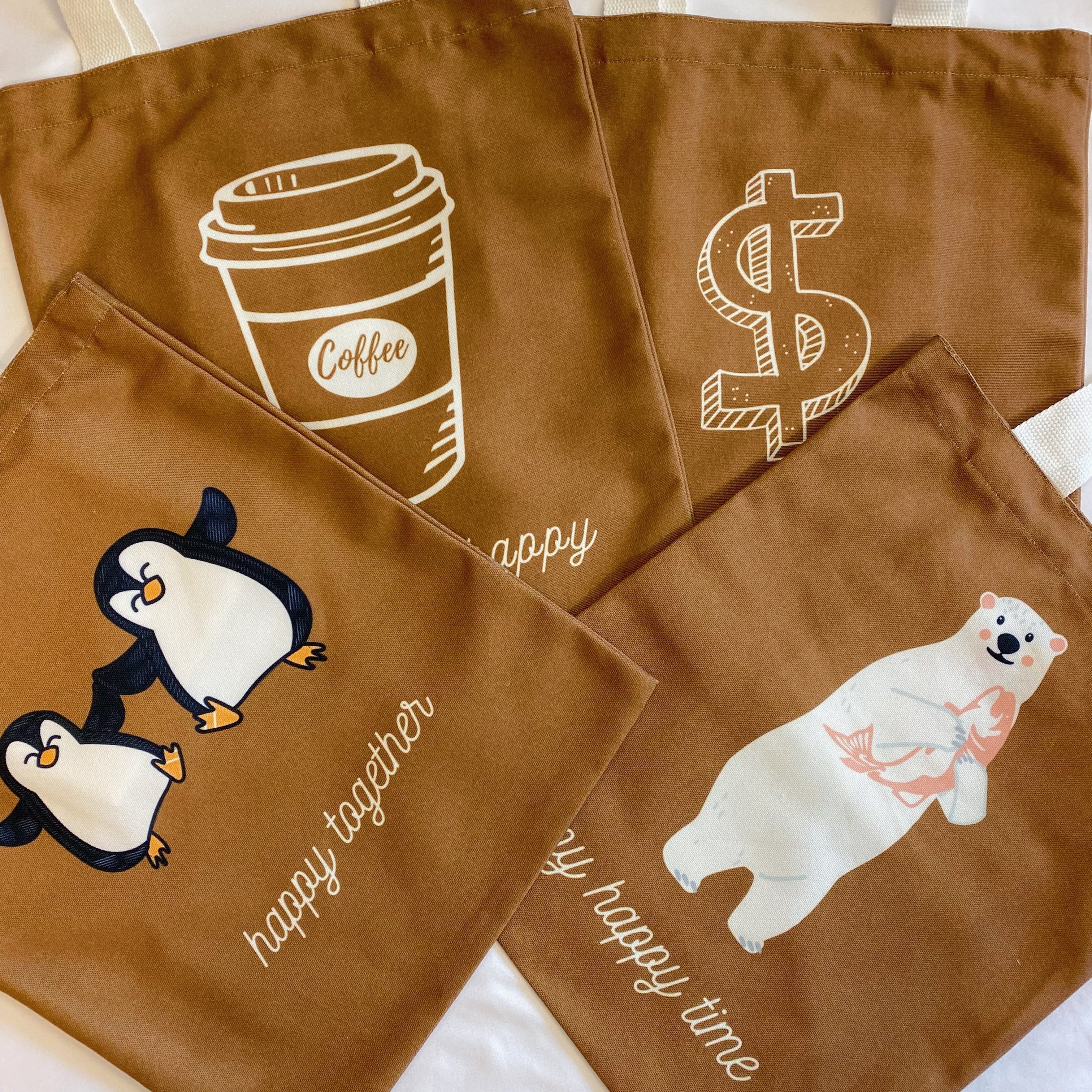White canvas tote bag with graphic print and shoulder strap carrying books and a laptop