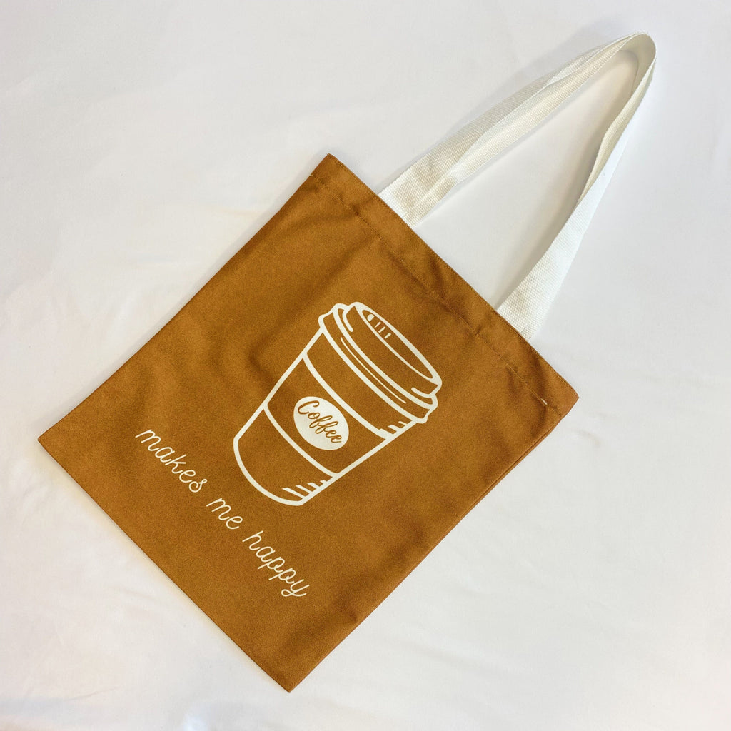 White canvas tote bag with graphic print and shoulder strap carrying books and a laptop — view 5