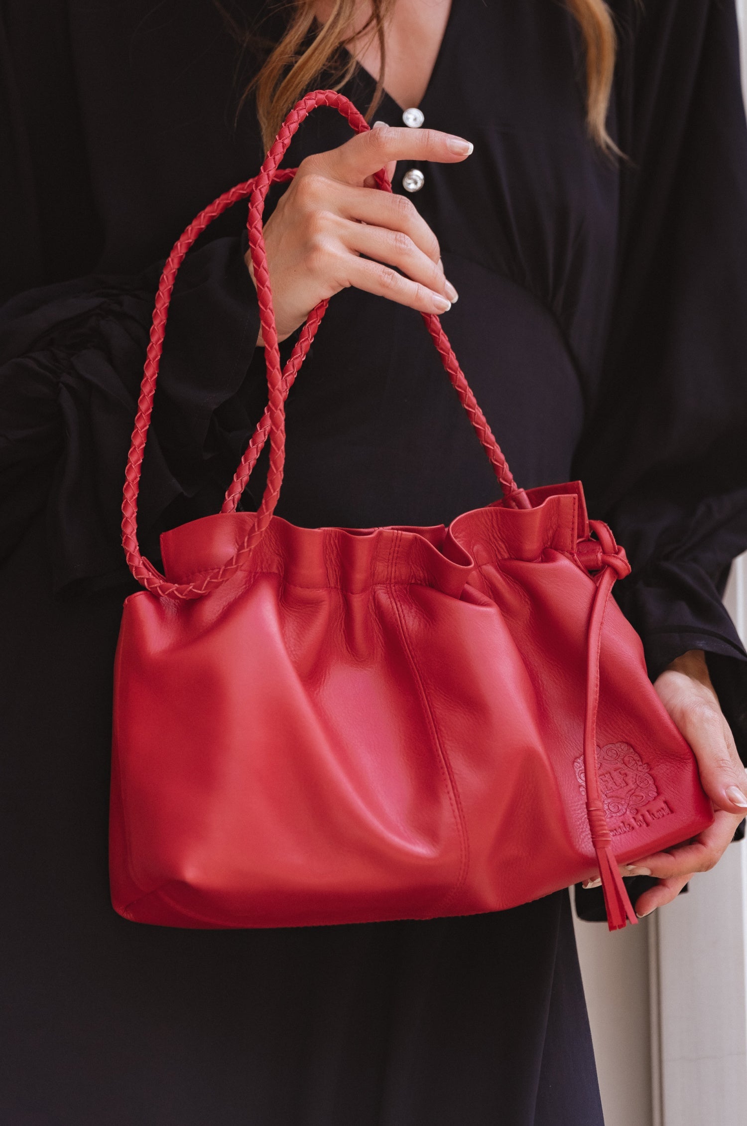 Red Etoile crossbody leather clutch bag with drawstring folds and a braided leather strap