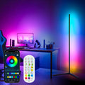 Black minimalist RGB corner floor lamp illuminating a living room with vibrant multicolored LED lighting