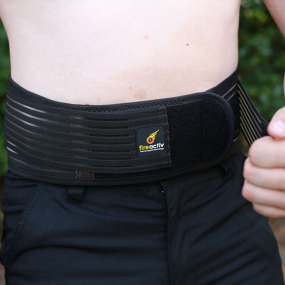 Self-heating back support belt in black worn around the waist for lower back pain relief — view 10