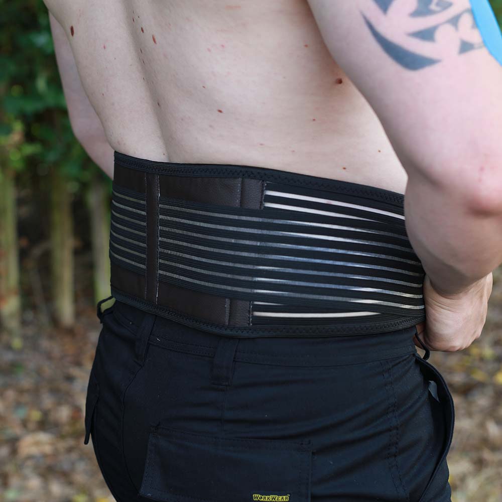 Self-heating back support belt in black worn around the waist for lower back pain relief