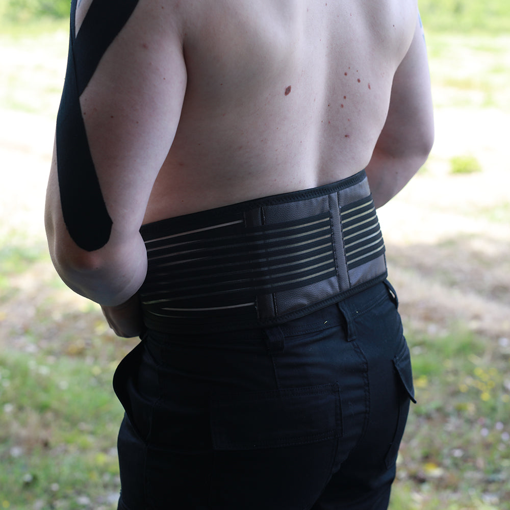Self-heating back support belt in black worn around the waist for lower back pain relief — view 7