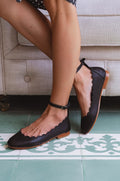 Black genuine leather Fleur scalloped ballet flats with adjustable ankle strap and round toe.