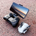 Foldable mini quadcopter drone with HD camera and remote control transmitter in black.