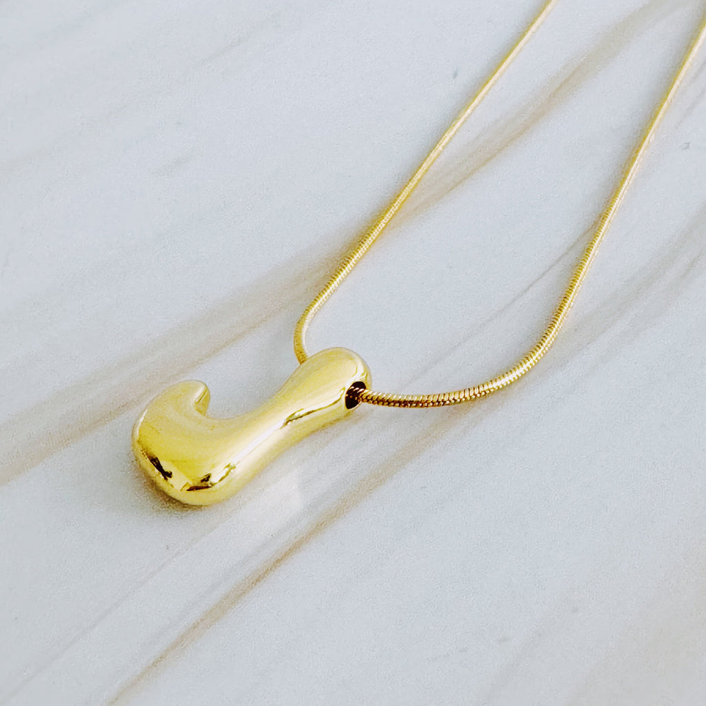 Gold plated balloon letter initial necklace with a stainless steel chain on a plain background — view 5